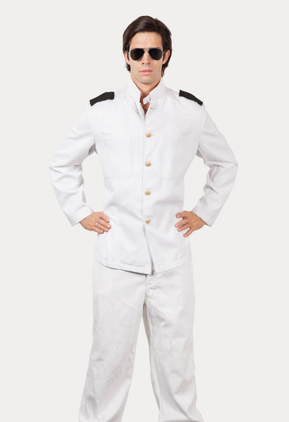 Portrait of young navy officer standing against gray background - Foto, immagini
