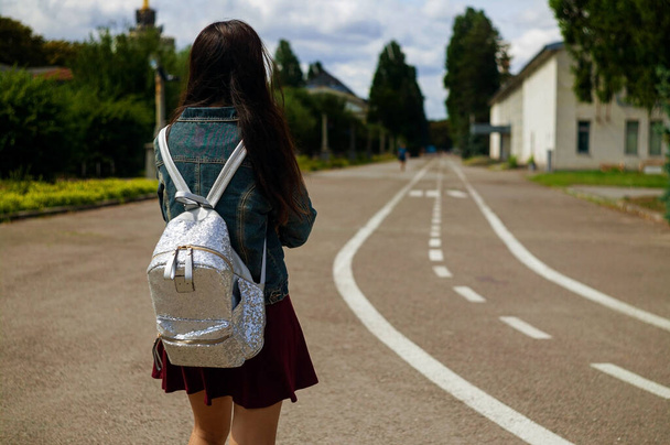 Vista trasera de mujer joven con mochila en el camino
 - Foto, imagen