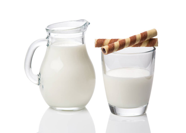 kruik en glas met melk en wafels geïsoleerd op witte achtergrond - Foto, afbeelding