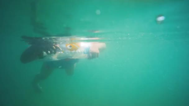 Criança nadando com cinto de vida anel, vista subaquática das pernas da criança
 - Filmagem, Vídeo