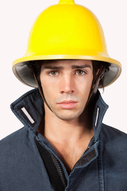 Portrait of young fireman against gray background - Foto, Imagem