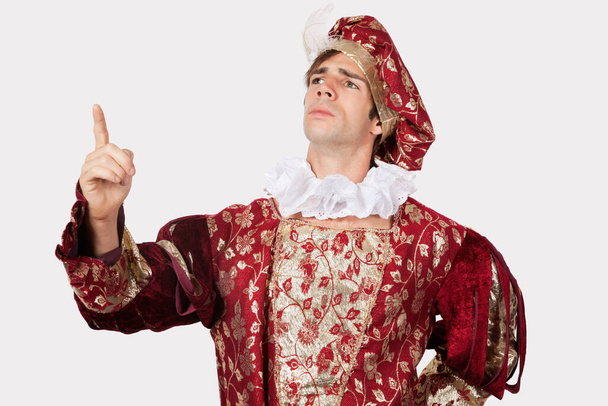 Young man in old-fashioned costume gesturing against gray background - Foto, Imagen