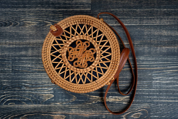 Modern stylish round straw bag on the wooden background, close up, top view - Foto, Imagem