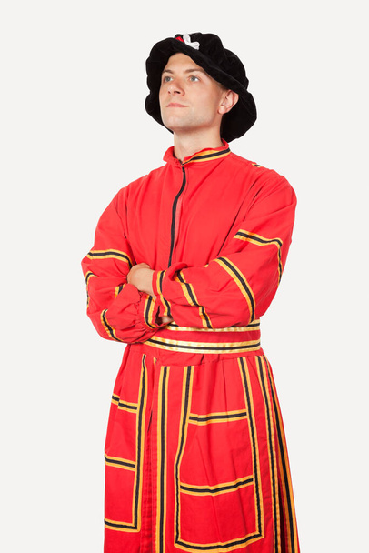Young man in orange costume with arms crossed against gray background - Foto, immagini