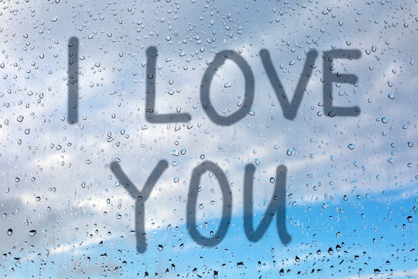  私はあなたを愛しています-ウィンドウペイン上の指で碑文。ガラスの上に雨が降っている。. - 写真・画像
