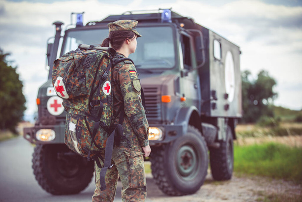 HANNOVER / GERMANY - JUNE 22, 2020: Paramedic of the German army with an emergency backpack stands at a military ambulance - Fotó, kép