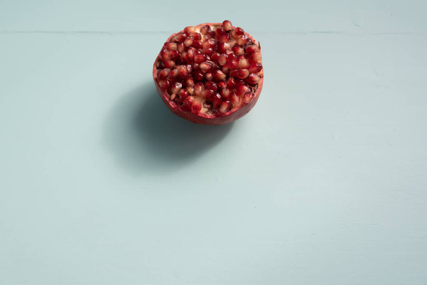 Half pomegranate covered by seeds on top center with light green copy space - Fotó, kép