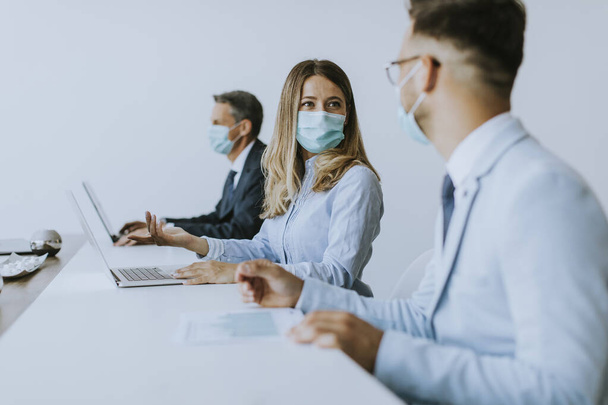 Üzletemberek csoportjának találkozója van és az irodában dolgoznak, és maszkot viselnek a koronavírus elleni védelemért. - Fotó, kép
