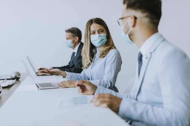 Üzletemberek csoportjának találkozója van és az irodában dolgoznak, és maszkot viselnek a koronavírus elleni védelemért. - Fotó, kép
