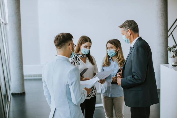 顔のマスクを身に着けている間、ビジネスパートナーは、オフィスでのビジネス結果を立って見て、ウイルス対策 - 写真・画像
