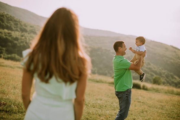 Молода сім'я розважається на відкритому повітрі в літньому полі
 - Фото, зображення
