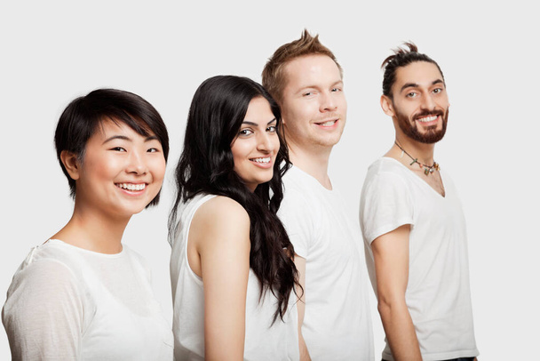 Side view of young multi-ethnic friends in casuals smiling over white background - Foto, imagen