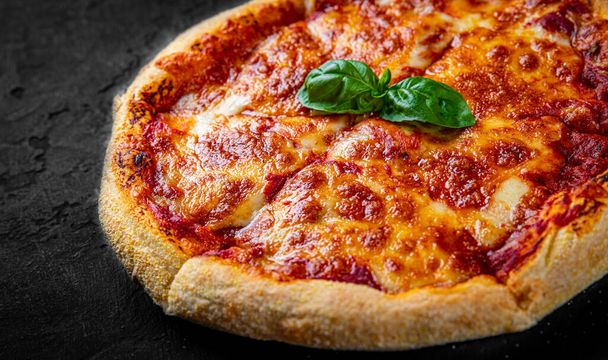 sliced Pizza with Mozzarella cheese, Tomatoes, pepper, Spices. Italian pizza. Pizza Margherita or Margarita on Dark grey black slate background - Foto, Bild