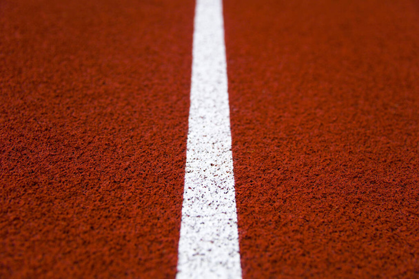 Primer plano de la línea blanca en pista de atletismo del estadio rojo
 - Foto, Imagen