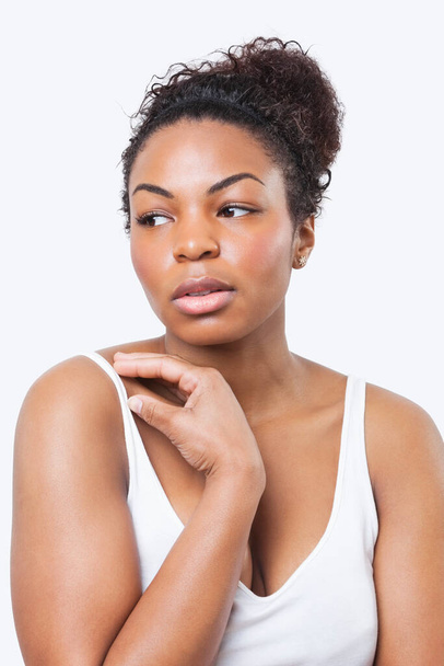 Задумчивая афроамериканская молодая женщина смотрит в сторону на белом фоне - Фото, изображение