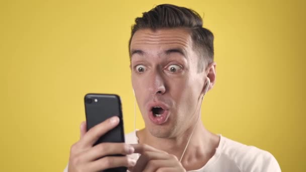 Ενθουσιασμένος νικητής άνθρωπος κρατήσει smartphone αισθάνονται κατάπληκτοι με το κινητό online στοίχημα νίκη app bet σε κίτρινο φόντο, χαρούμενος εκστατικός αρσενικός χρήστης χρήση ματιά στο κινητό τηλέφωνο γιορτάσουν διαβάσει καλά νέα - Πλάνα, βίντεο