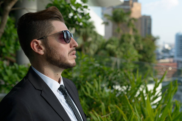 Портрет красивого бородатого латиноамериканского бизнесмена с природой в городе на открытом воздухе - Фото, изображение