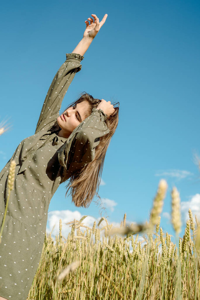 ears of wheat. young girl in dress shows emotion. emotionally jumps and runs on a summer field with spikelets. Hair flying in the wind, lifestyle Concept of cosmetology, harvest, farm - Фото, зображення