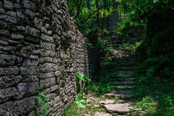 Un sendero de escalones de hormigón entre antiguas casas abandonadas de un antiguo pueblo situado en medio de la exuberante selva tropical cerca de Yangshuo, China
 - Foto, imagen