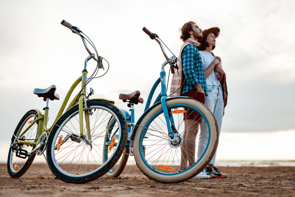 Zwei Personen stehen mit blauen und grünen Fahrrädern am Strand - Foto, Bild