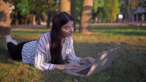 Atraktivní žena na trávě s notebookem, dálkové ovládání online na volné noze - Záběry, video