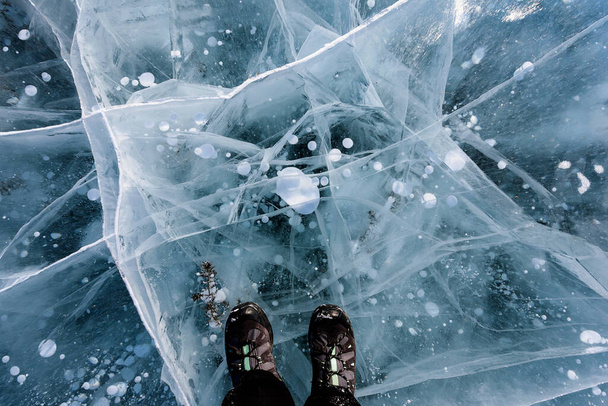 Hermoso hielo del lago Baikal con grietas abstractas con zapatos. Vista superior - Foto, Imagen
