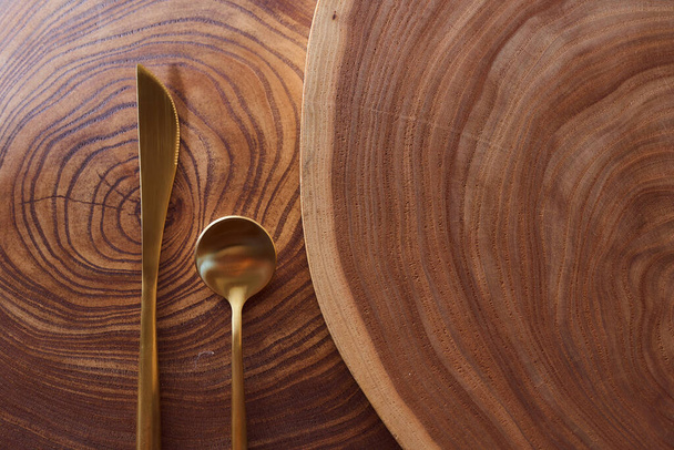 La forchetta d'oro si trova su una fetta di albero. tavolo in legno. Con spazio di copia. - Foto, immagini
