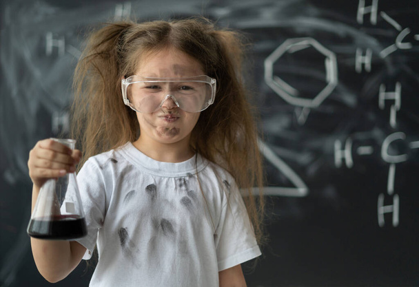 Маленькая девочка в школьной лаборатории проводит эксперименты на уроке химии. Взрыв во фляжке. Снова в школу. - Фото, изображение