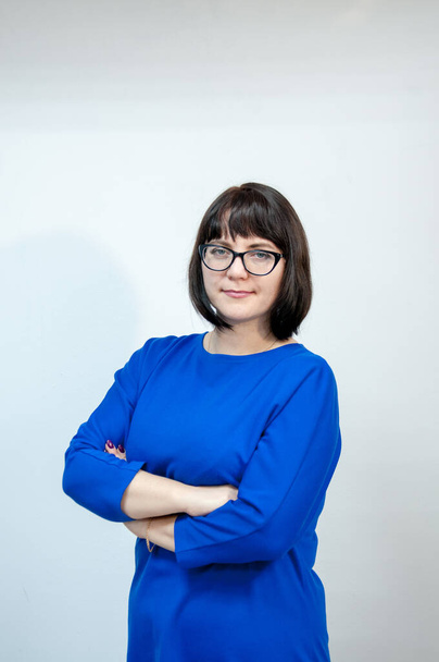 Portrait of a serious businesswoman brunette in a blue dress with glasses - 写真・画像