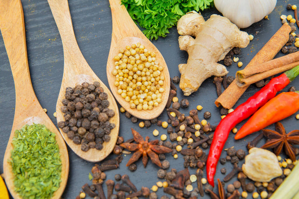 Close up of various herbs and spices in wooden spoons on the wooden table background - 写真・画像