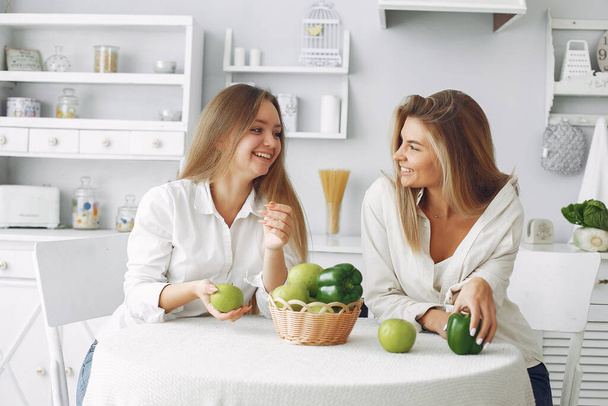 Mooie en sportieve meisjes in een keuken met een groente - Foto, afbeelding
