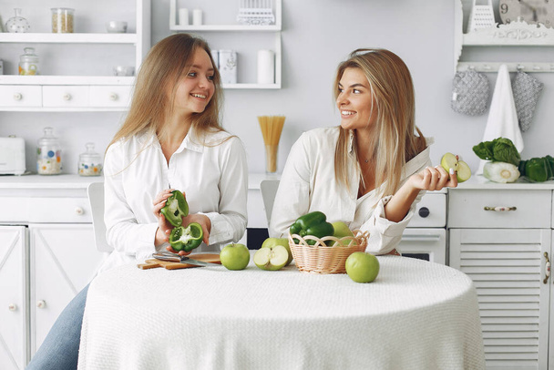 Beautiful and sporty girls in a kitchen with a vegetables - Zdjęcie, obraz