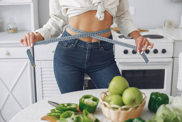 Beautiful and sporty girl in a kitchen with a vegetables - Foto, Imagen
