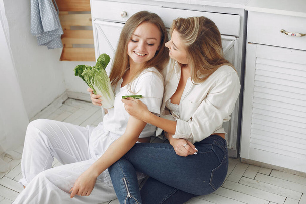 Beautiful and sporty girls in a kitchen with a vegetables - Fotó, kép