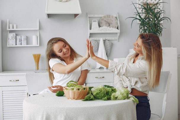Beautiful and sporty girls in a kitchen with a vegetables - Photo, Image
