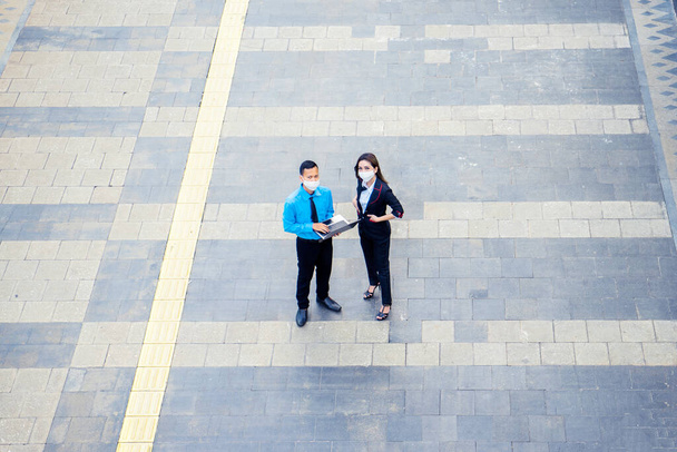Aerial view of two business people wearing mask while looking at the camera while standing on the sidewalk - Foto, Imagem