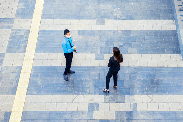 Top down view of young business couple wearing mask and standing on the sidewalk while chatting together - Foto, immagini