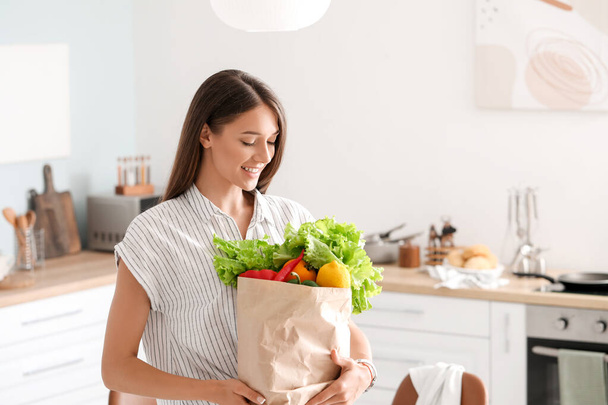 Young woman with fresh products from market at home - Foto, imagen