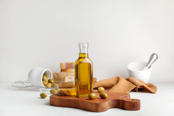 Bottle of tasty olive oil and bread on white background - Photo, image