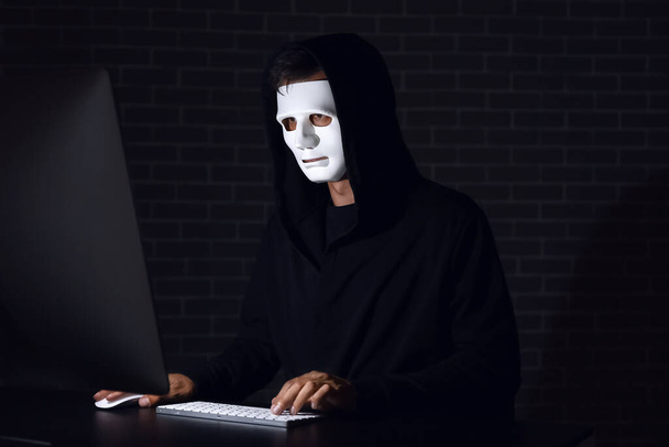Professional hacker working on computer at table in dark room - Φωτογραφία, εικόνα