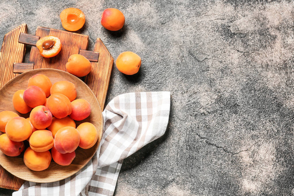Plate with tasty ripe apricots on grey background - Fotó, kép