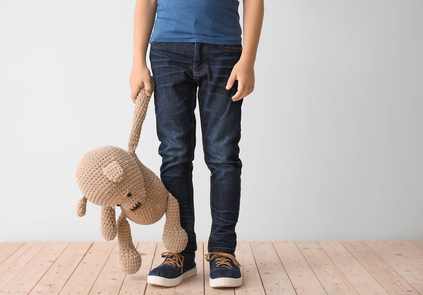 Маленький мальчик с аутизмом и игрушкой возле светлой стены - Фото, изображение