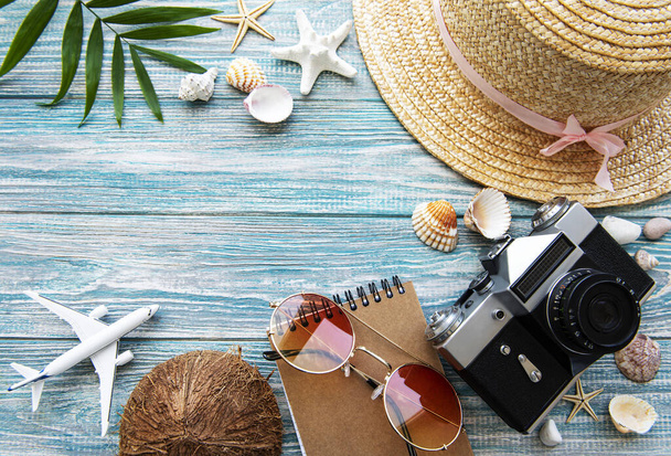 Концепция летнего путешествия. Старая кинокамера, шляпа, раковина и пальмовые листья на синем деревянном фоне. - Фото, изображение