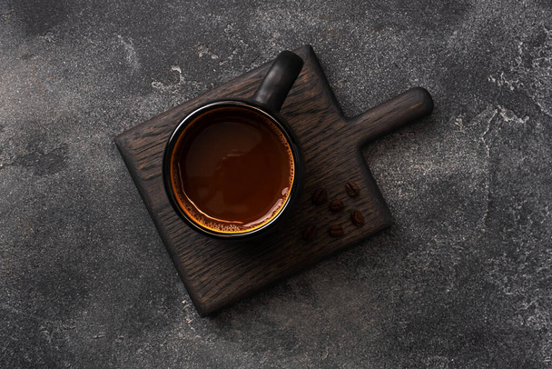 Black coffee in a Cup and coffee beans on a dark background. Top view Copy space. - Foto, afbeelding