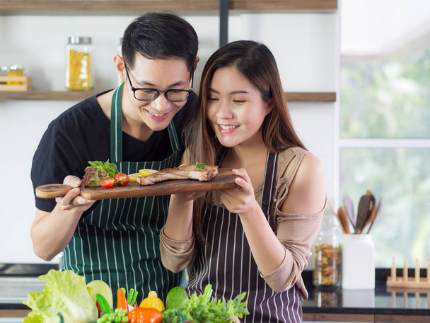 Young couple are very happy after helping to make steak at the kitchen. Concept of couple life - Foto, immagini
