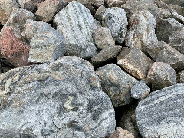 Achtergrondtextuur: veel grote stenen van verschillende vormen. Een stapel granieten rotsblokken. Concept - steen, hardheid, solide fundering - Foto, afbeelding
