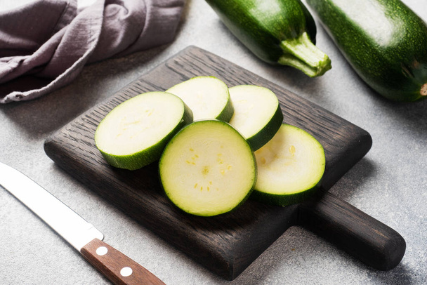 Fresh green zucchini cut into slices on a cutting Board. Concrete grey background. Close up. - Fotoğraf, Görsel
