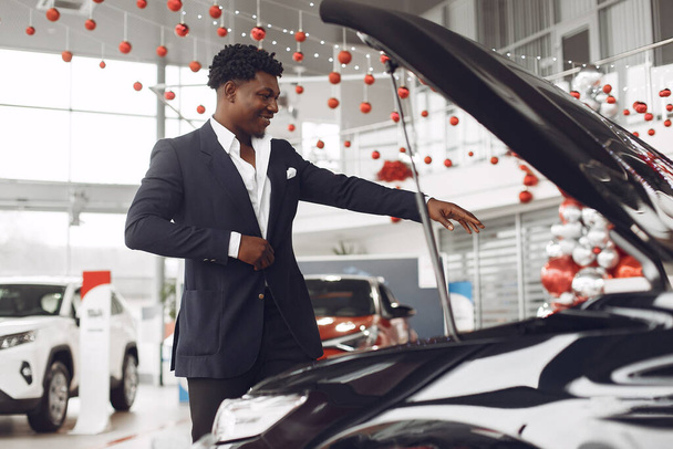 Handsome and elegant black man in a car salon - Photo, image