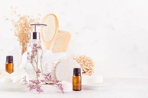 White bathroom interior with natural bamboo accessories and beauty products - essential oil in amber glass, towel, sponge, soap dispenser, brush, lavender on white wood board. - Φωτογραφία, εικόνα