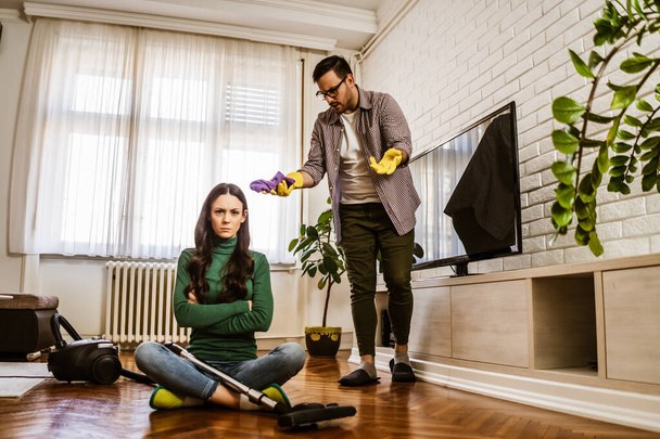 Woman is lazy. Man is telling her to continue cleaning their apartment. - Photo, image